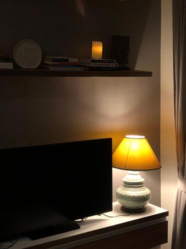 a lamp sitting on a table next to a television at Remote work friendly apartment with fast wifi - rooftop and gym in Chiang Mai