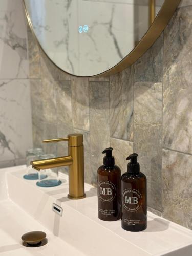 two bottles of mr and mrs shampoo sitting on a bathroom sink at Ellen Kensington in London