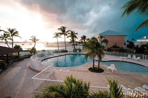 Baie NettleにあるStudio Coconut Sunset with poolのヤシの木が茂るビーチの隣にある大きなスイミングプール