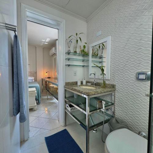 a bathroom with a sink and a toilet and a bedroom at Next to the sea, Central beach in Balneário Camboriú