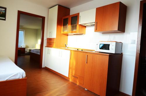 a kitchen with wooden cabinets and a microwave on a counter at Penzion Relax Martina in České Budějovice