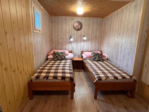 two beds in a room with wooden walls and wooden floors at Siedlisko Silna Nowa in Silna Nowa