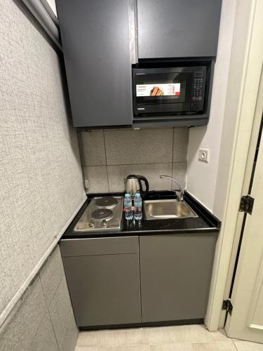 a small kitchen with a sink and a microwave at central apartment for rent 23 in Umm Uthainah