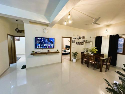 a living room with a table and a tv on a wall at ZoomStay - 3BHK Apartments in Varanasi