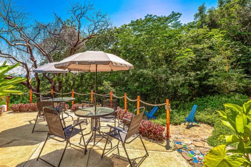 a patio with a table and chairs and an umbrella at Villa Buganvilia in Barra de Navidad