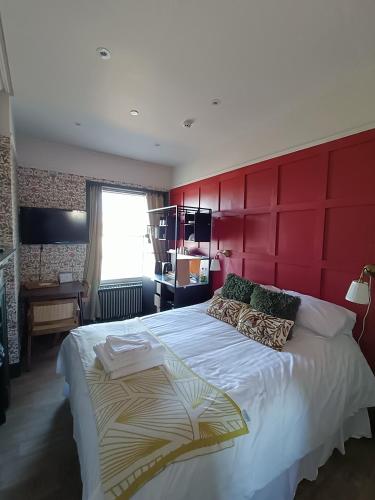 チェルトナムにあるRooms on The Promの赤い壁のベッドルーム1室(大型ベッド1台付)