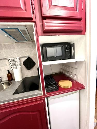 une armoire rouge avec un micro-ondes dans une cuisine dans l'établissement Magnifique studio cosy Paris 18, à Paris