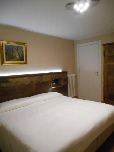 a bedroom with a white bed with a wooden headboard at La Vigne de Papagran in Aosta