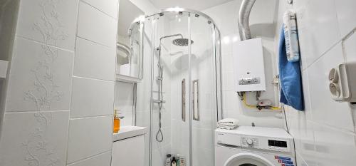 a white bathroom with a shower and a washing machine at Mieszkanie dwupokojowe z balkonem, blisko parku in Jastrzębie Zdrój