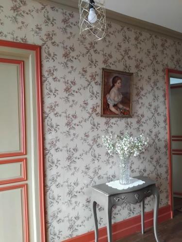 une table avec un vase de fleurs sur un mur dans l'établissement Esyom's, à Coulonces