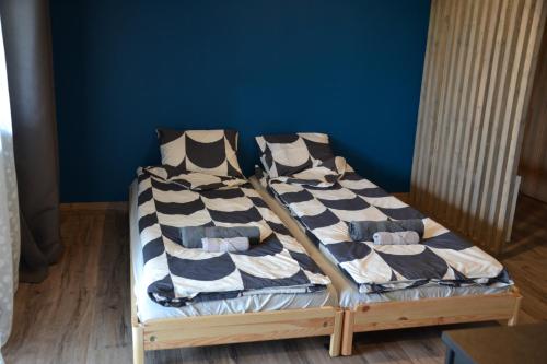 two beds in a room with a blue wall at Hotel Mergera in Mērsrags