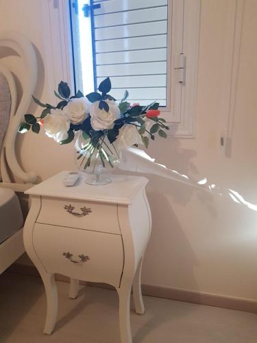 a vase of flowers on a table next to a window at Cozy House near the beach in Regina Gardens in Paphos