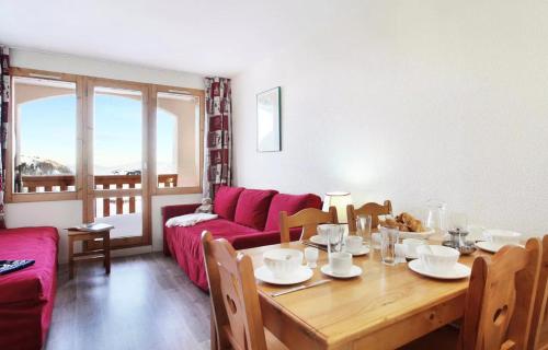 un salon avec une table et un canapé rouge dans l'établissement Résidence La Licorne - maeva Home - Appartement 3 pièces 6 personnes - Confort MAE-9971, à La Plagne