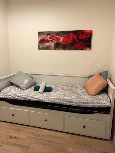 un lit avec deux oreillers et un tableau au mur dans l'établissement Charmant studio en centre-ville de Mulhouse - Equipé, à Mulhouse