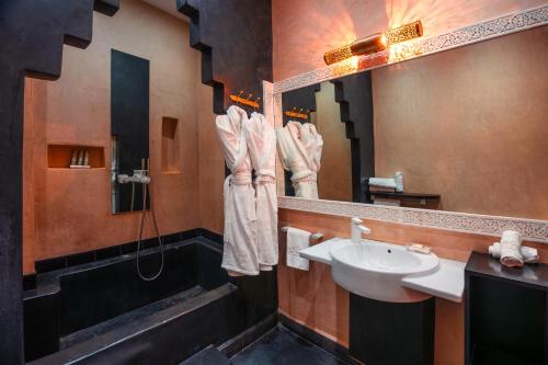 a bathroom with a sink and a shower and a mirror at Riad L'ECOLE in Marrakech