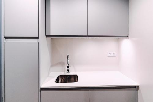 a kitchen with a sink and white cabinets at Estrella De Mar - Boutique ApartHotel in Benidorm