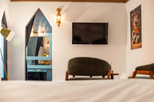 a bedroom with a bed and two chairs and a tv at Riad L'ECOLE in Marrakech