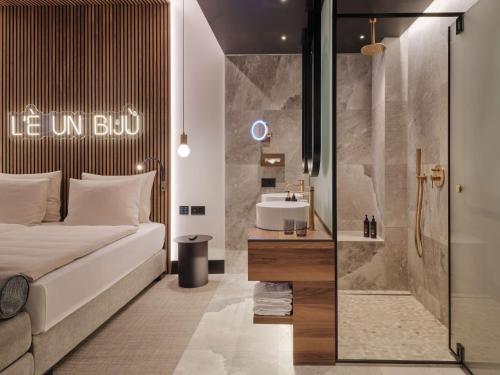 a bedroom with a bed and a bathroom with a sink at Dorint Resort & Spa Locarno-Riazzino in Riazzino
