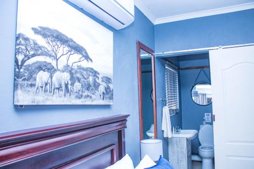 a bathroom with a painting of elephants on the wall at Presidents Boutique Lodge by Ilawu in Vryheid