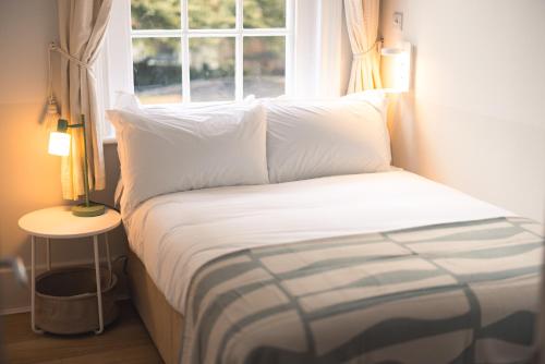 a bed with white pillows in a room with a window at The Regency by Nestor in London