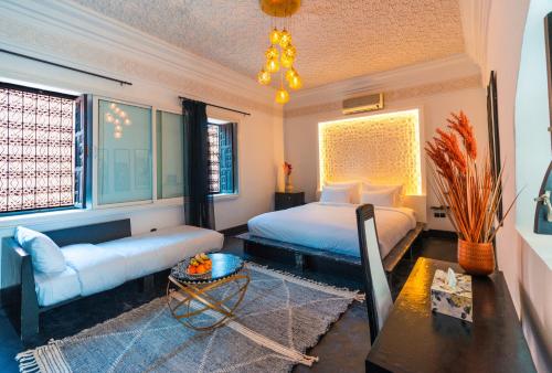 a bedroom with a bed and a couch and a table at Riad L'ECOLE in Marrakech