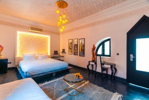a bedroom with two beds and a table at Riad L'ECOLE in Marrakech