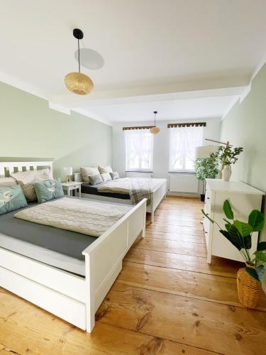 two beds in a white bedroom with wooden floors at Stadtnah & Naturverbunden in Luckenwalde