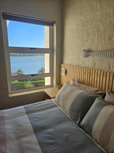 a bedroom with a bed and a large window at Be Lazy with a Sea View in Jeffreys Bay