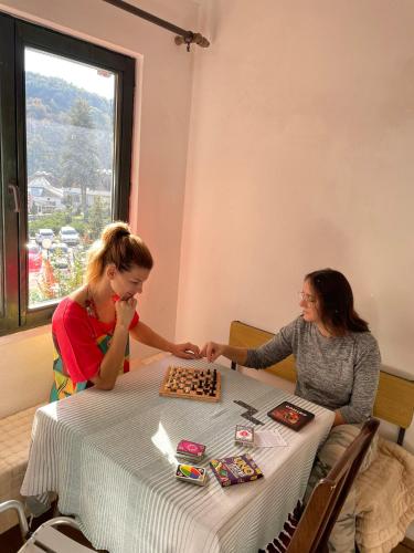 two women sitting at a table playing chess at Lola in Prolomska Banja