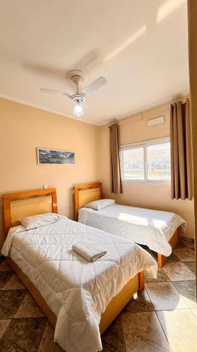 two beds in a bedroom with a window at Hotel Pousada Do Leão in Lençóis Paulista