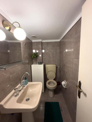 a bathroom with a white sink and a toilet at Spacious Artistic Flat With Private Parking in Thessaloniki