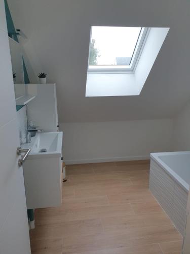 une salle de bain blanche avec un lavabo et une fenêtre dans l'établissement Maison de vacances, à Longues-sur-Mer