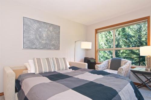 a bedroom with a bed and two chairs and a window at Aspens on the Mountain Ski In Out in Whistler