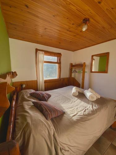 a large bed in a room with a wooden ceiling at Complejo Don Cirilo in Villa Pehuenia
