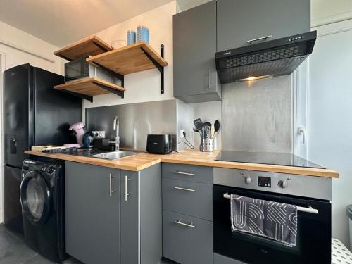 - une cuisine avec des placards gris et un lave-linge/sèche-linge dans l'établissement Le Jules Verne, proche de la Gare, à Boulogne-sur-Mer