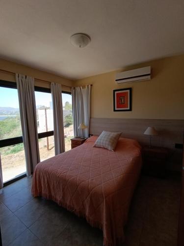 a bedroom with a bed and a large window at Complejo Refugio Playa Perelli in Villa Carlos Paz