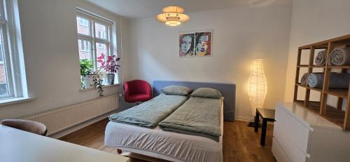 a bedroom with a bed and a red chair at Townhouse in the Center Free Parking in Aalborg