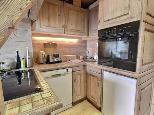 une cuisine avec des armoires en bois et un appareil noir dans l'établissement Appartement de standing Mont d'Arbois, à Megève