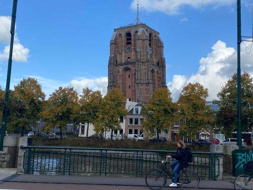a woman riding a bike in front of a clock tower at Vintage appartement in Pakhuis Friesland in centrum in Leeuwarden