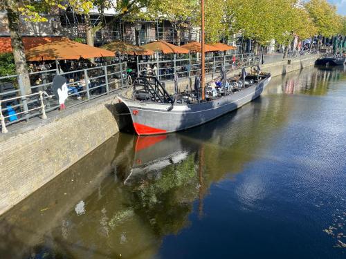 a boat is docked in a river next to a pier at Vintage appartement in Pakhuis Friesland in centrum in Leeuwarden