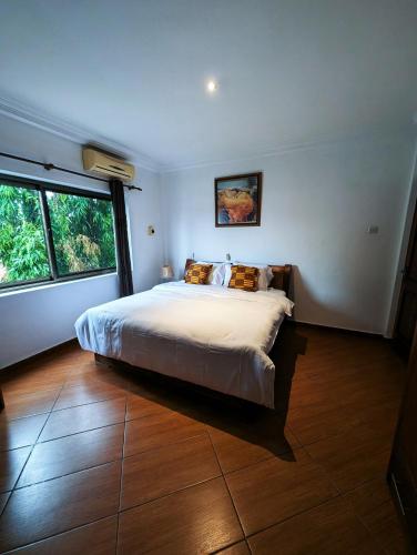 a bedroom with a large bed and a large window at Luxor garden 1 bedroom Apartment 3A in Accra