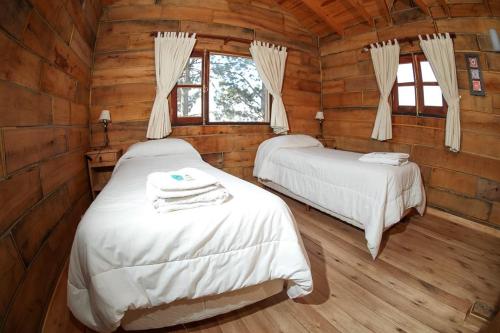 a bedroom with two beds in a log cabin at Cabañas del Peñón in La Cumbrecita