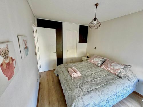 a bedroom with a bed with pink slippers on it at Apartamento en exclusivo barrio Lomas de san Andrés con estacionamiento in Concepción