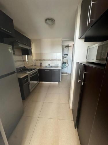 a small kitchen with black cabinets and a tile floor at Amplio departamento con balcon in San Luis Potosí