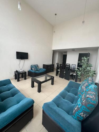 a living room with blue couches and a tv at Amplio departamento con balcon in San Luis Potosí