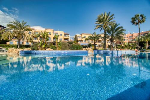 a large swimming pool with palm trees and buildings at Limnaria Gardens H 202 in Paphos City