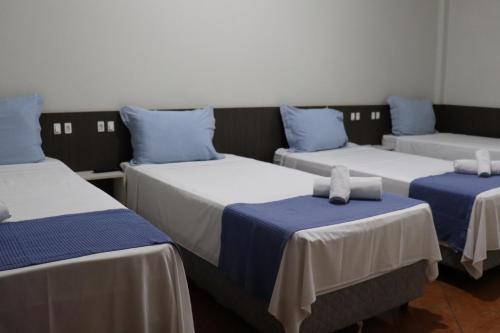 a room with three beds with blue and white sheets at Eco Hotel in Navegantes