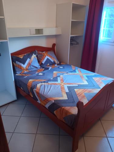 a bed with a quilt on it in a bedroom at Pagerie bas de villa in Les Trois-Îlets