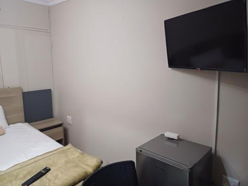 a room with a tv and a bed and a chair at Willow Guest house in Vereeniging