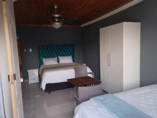 a bedroom with two beds and a table at Willow Guest house in Vereeniging